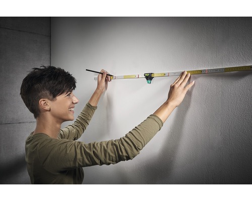 Žena používá skládací metr s integrovanou vodováhou na stěně