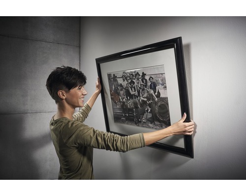 Žena drží zarámovaný umělecký tisk na zdi