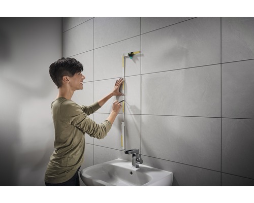 Žena měří stěnu skládacím metrem v koupelně