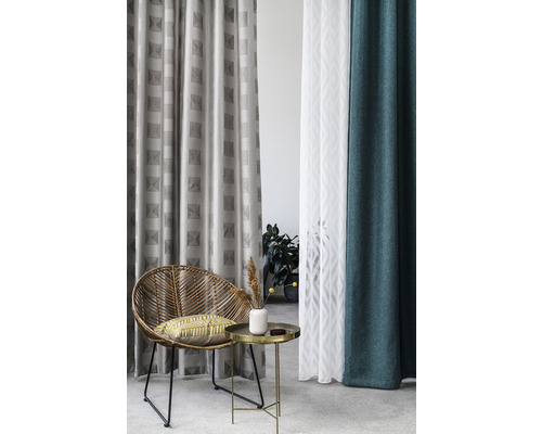 Obývací pokoj s ratanovým křeslem, odkládacím stolkem a různými závěsy se vzory