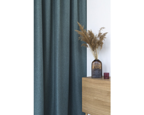 Dekorativní, strukturovaný závěs vedle dřevěné skříně s vázou a sušenými květinami