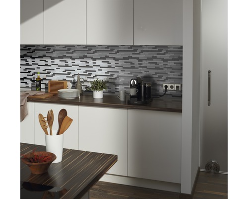 Kuchyňská scéna s mozaikovými obklady, pracovní deskou a kuchyňským náčiním