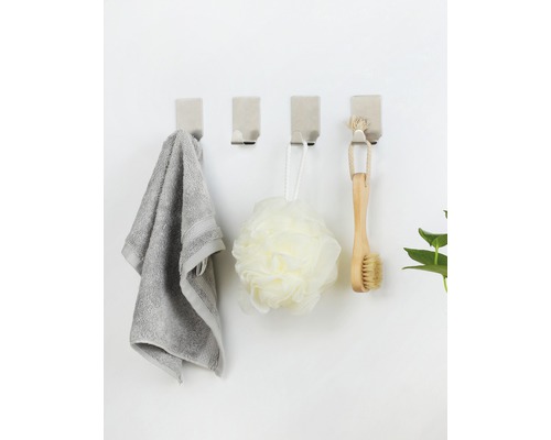 Čtyři nástěnné háčky s ručníkem, koupelovou houbou a kartáčem na stěně
