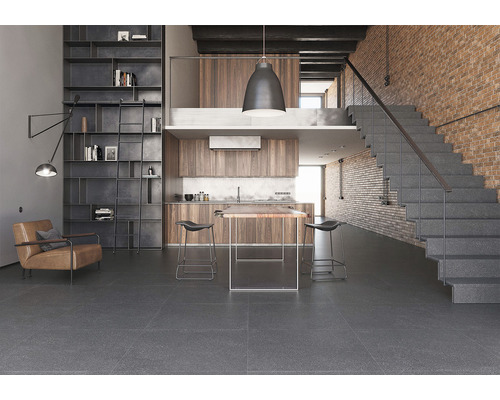 Světlý pokoj s regály, posezením, kuchyní, jídelním stolem, barovými stoličkami a schodištěm s kamenným vzhledem.