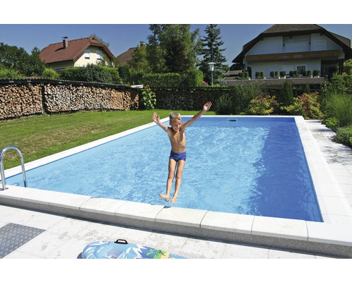 Chlapec skáče do obdélníkového bazénu na zahradě.