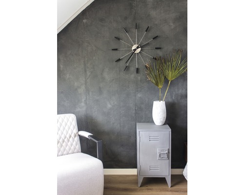 Interiérová fotografie pokoje s křeslem, hodinami, vázou s rostlinami a kovovou skříní