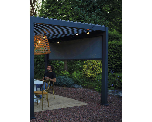 Scéna s hliníkovou pergolou, vybavenou markýzou, závěsnou lampou a světelným řetězem, vytvářející relaxační venkovní prostor.
