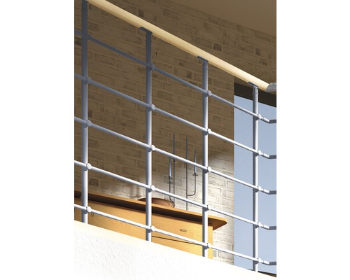 Kovové zábradlí s dřevěným madlem před cihlovou zdí