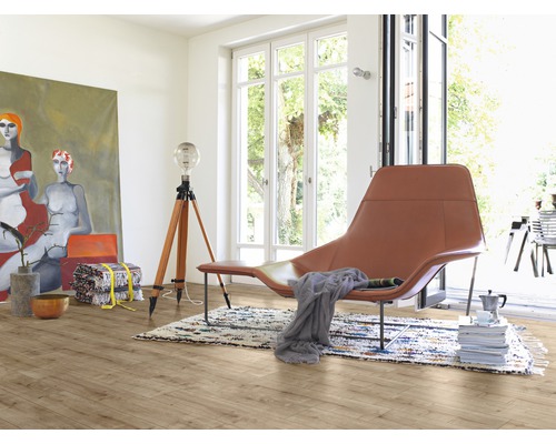 Světlá místnost s dřevěnou podlahou, křeslem, lampou a malbou