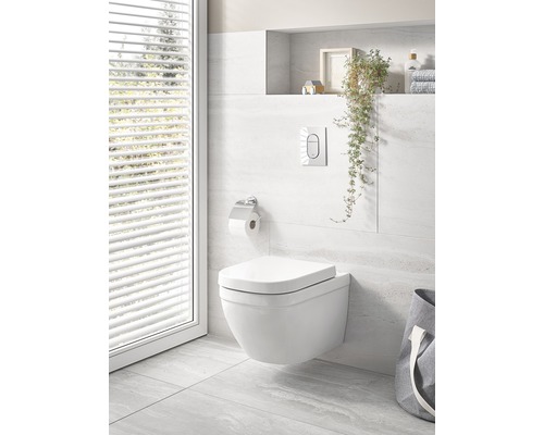 Závěsná toaleta v světlé koupelně s okny a dekoracemi.