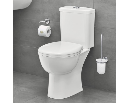 Bílá stojící toaleta s nádržkou, držákem toaletního papíru a štětkou na WC v koupelně