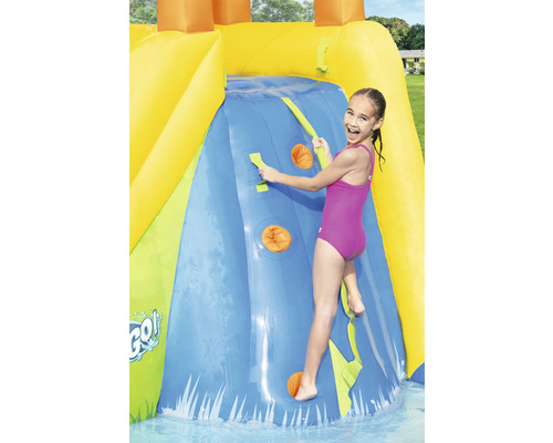 Dívka leze na nafukovací vodní skluzavku s lezeckou stěnou