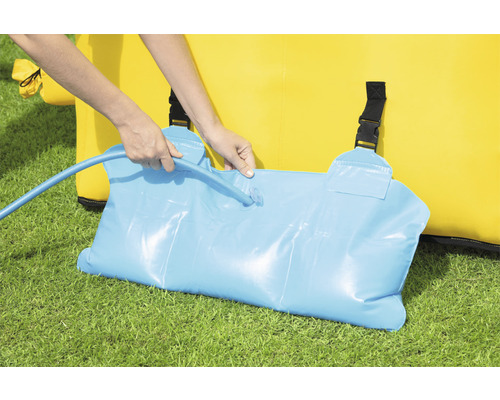 Osoba plní vodní vak pro zatížení skákacího hradu pomocí vodní hadice