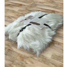 Bílý koberec z umělé kožešiny, srolovaný a označený etiketou na dřevěné podlaze