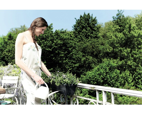 Žena zalévá květiny na balkoně konví