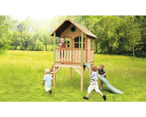 Dřevěný hrací domek se skluzavkou a hrajícími si dětmi na zahradě