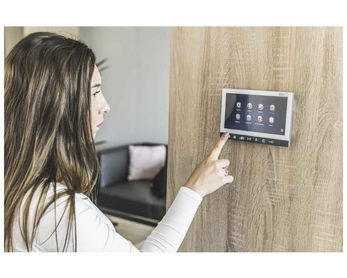 Žena ovládá dotykový displej interkomu na dřevěné stěně