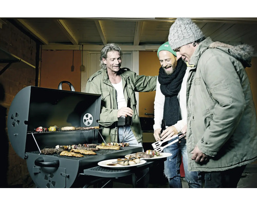 Tři muži stojí kolem grilu s masem, zeleninou a špízy.