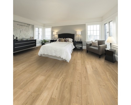 Ložnice s dřevěnou podlahou, postelí, komodou a křeslem.