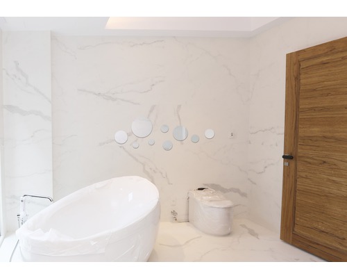 Moderní koupelna s volně stojící vanou, toaletou a kulatými zrcadly jako dekorace