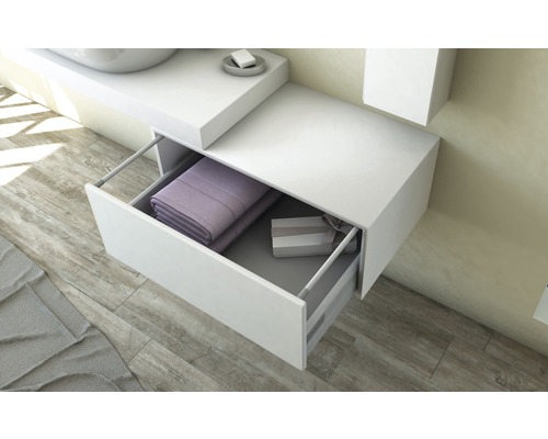 Bílá skříňka pod umyvadlo s otevřenou zásuvkou, vyplněná ručníky a dárkovou krabičkou