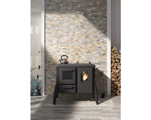 Interiérová fotografie s kamny, čajovou konvicí, palivovým dřívím a zděnou stěnou