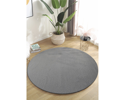 Kulatý šedý koberec ve světlé místnosti