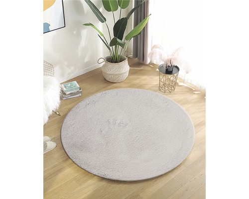 Zařízení s kulatým kobercem z umělého vlákna na dřevěné podlaze ve světlé místnosti.