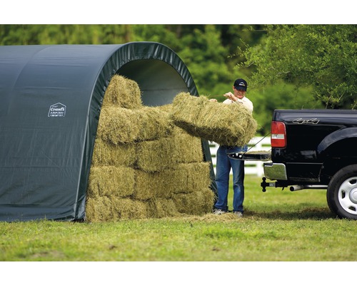 Sklad sena s mužem nakládajícím balíky sena na nákladní auto