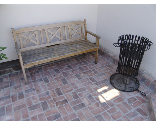 Scéna s dřevěnou lavicí a košem na dřevo na terase