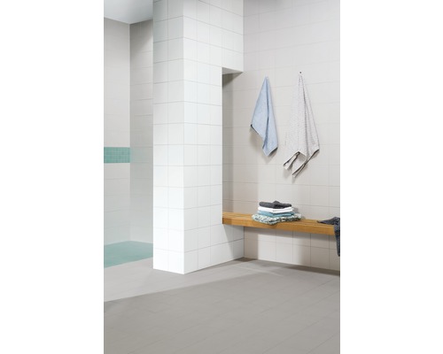 Moderní koupelna s bílými obklady, dřevěnou lavicí a ručníky