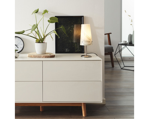 Obývací pokoj s komodou, stolní lampou, pokojovou rostlinou a dekorací