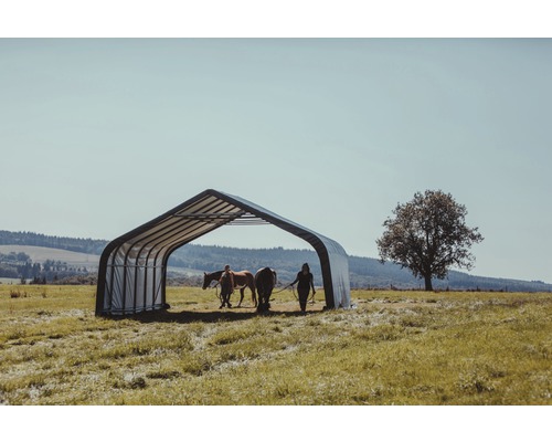 Přístřešek pro koně na louce se dvěma koňmi a dvěma lidmi