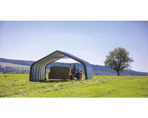 Scéna s přístřeškem pro zemědělské stroje a balíky sena na louce