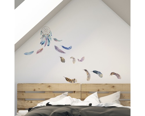 Ložnice s nástěnnou samolepkou lapače snů a peří nad dřevěnou postelí