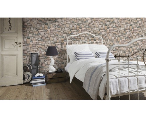 Ložnice s postelí, lampou a tapetou se vzorem zdiva