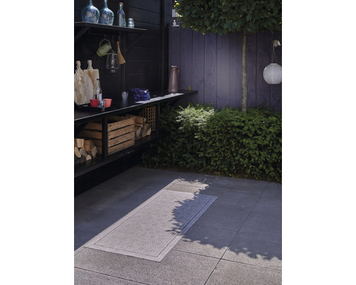 Venkovní prostor s úložným prostorem na dřevo, pracovní plochou a vzorovaným kobercem na zemi.