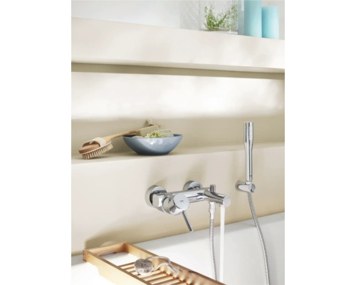 Fotografie koupelny s armaturou, ruční sprchou, mýdlem, kartáčem a dřevěnou policí