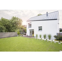 Pohled na moderní dům se zahradou, trávníkem a dřevěným plotem