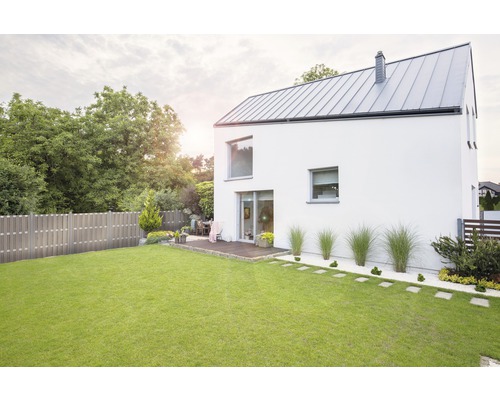 Pohled na moderní dům se zahradou, trávníkem a dřevěným plotem