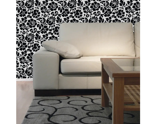 Obývací pokoj s pohovkou, dřevěným stolem, vzorovaným kobercem a květinovou tapetou