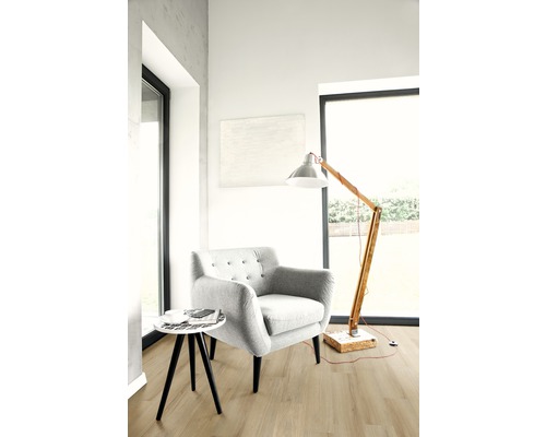 Světlý obývací pokoj s křeslem, stojací lampou a malým stolem na dřevěné podlaze