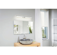 Světlá koupelna s umyvadlem, zrcadlem, osvětlením a oknem.