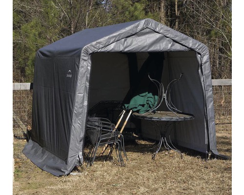 Šedý domek na nářadí se zahradním stolem a židlemi uvnitř