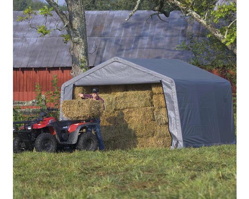 Šedý skladovací stan s balíky sena a osobou