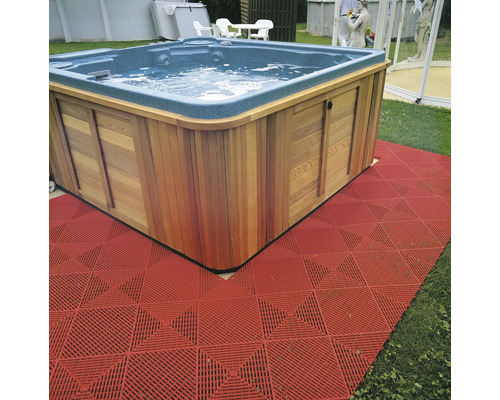 Čtvercová vířivka s dřevěným obložením a červenou podlahovou krytinou v zahradě.