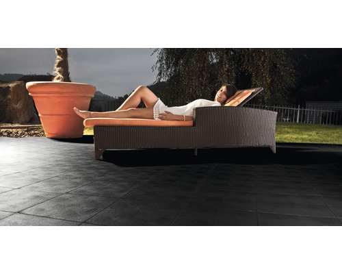Žena odpočívá na lehátku na terasových dlaždicích