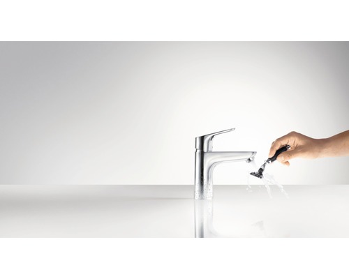 Páková baterie s rukou a holicím strojkem pod tekoucí vodou