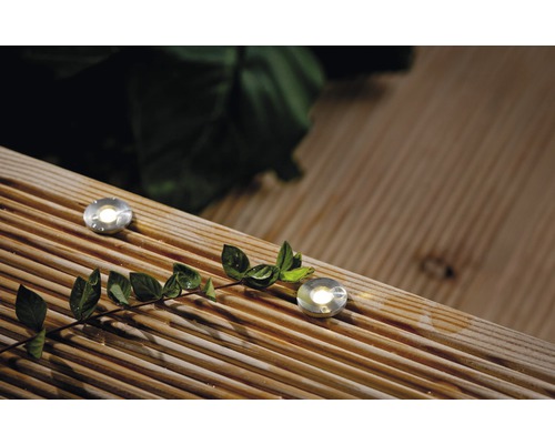 Dvě zemní svítidla jsou zapuštěna v dřevěné terasové podlaze a svítí.