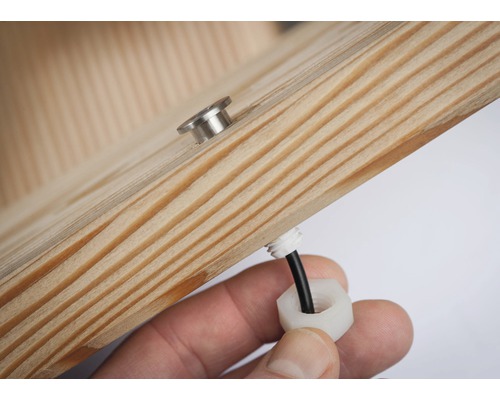 Detailní pohled na dřevěný prvek se šroubem a kabelovou průchodkou.